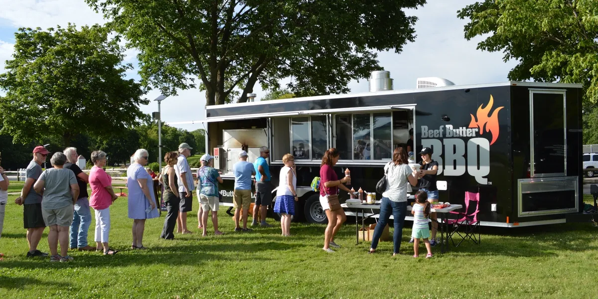 A group of people standing around in front of food trucks.