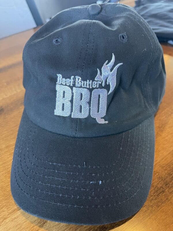 A black hat with the words beef better bbq on it.