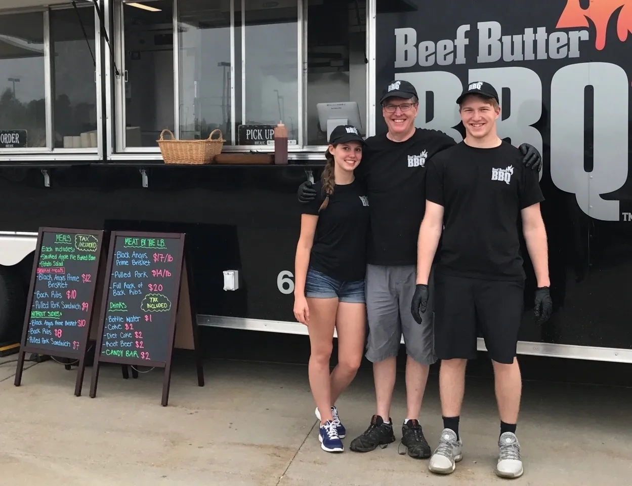 Three people standing in front of a food truck.