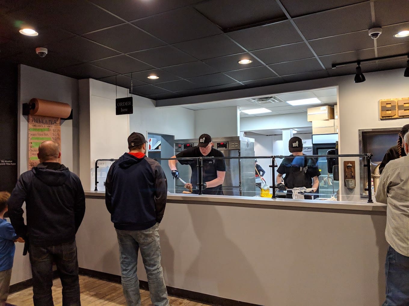 A group of people standing around in front of a counter.