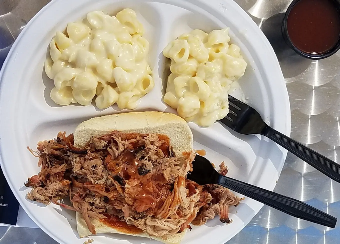 A plate of food with macaroni and cheese, pulled pork sandwich.