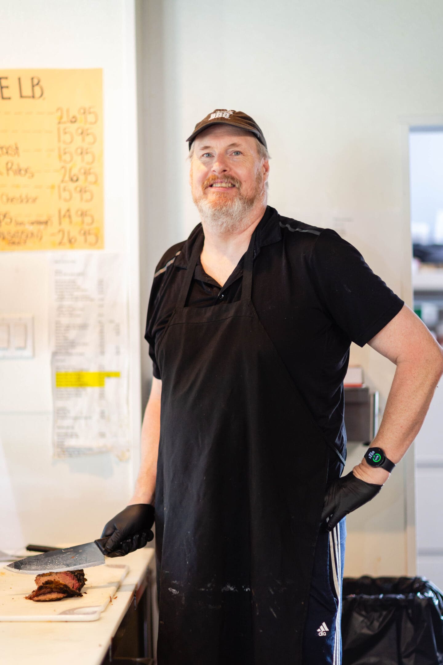 A man in black shirt and hat standing next to a chair.