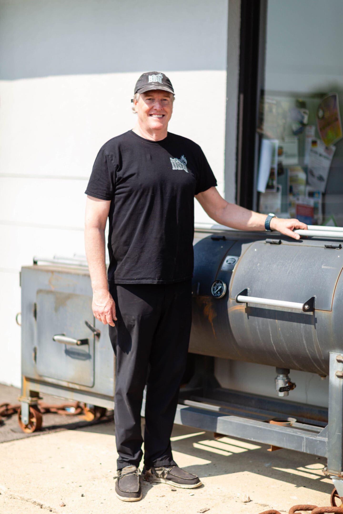 A man standing next to an outdoor grill.