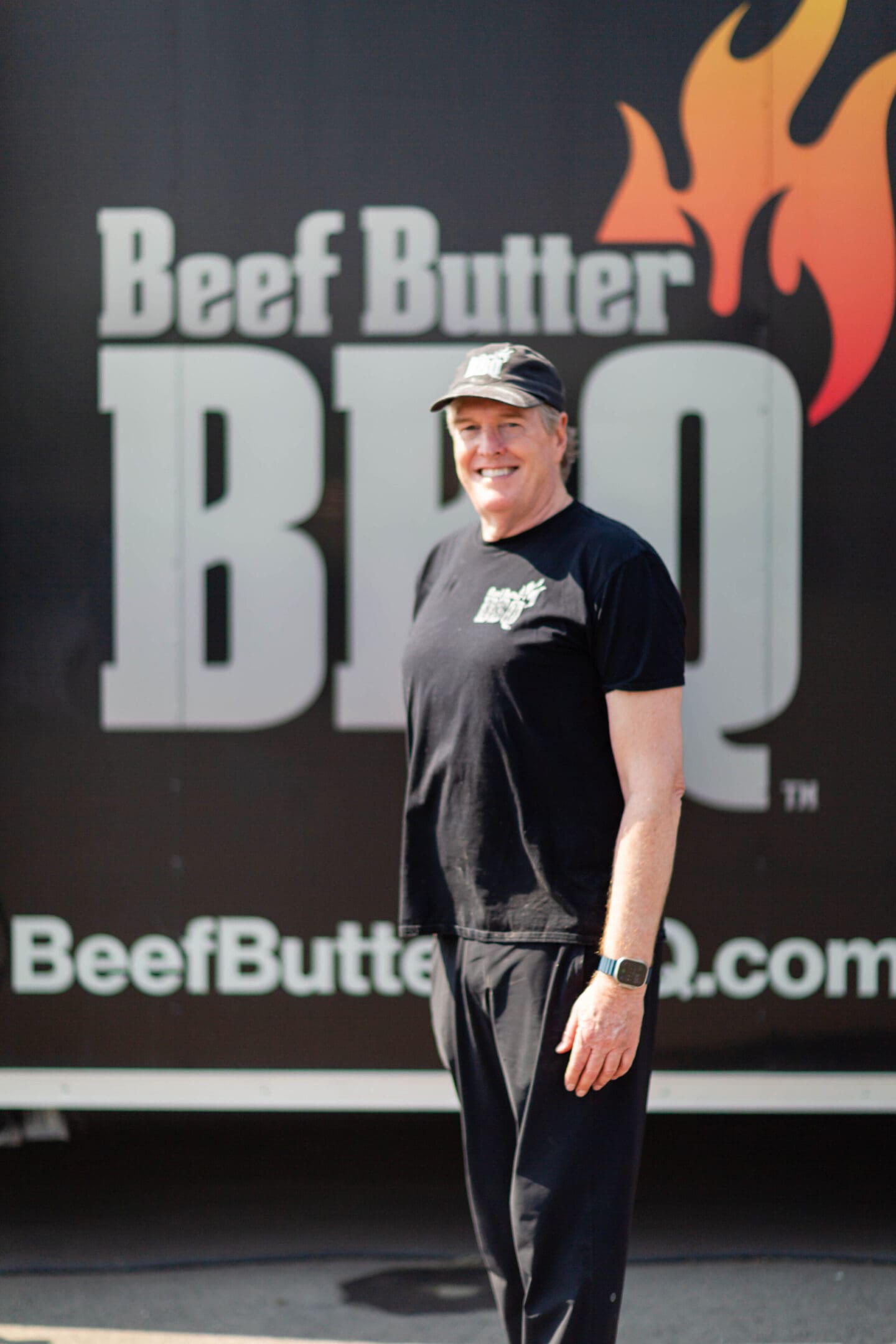 A man standing in front of a beef butter bbq sign.