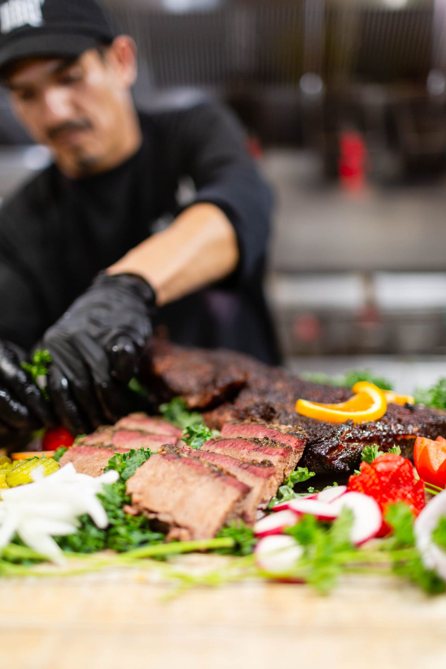 A person in black gloves cutting meat on top of a table.