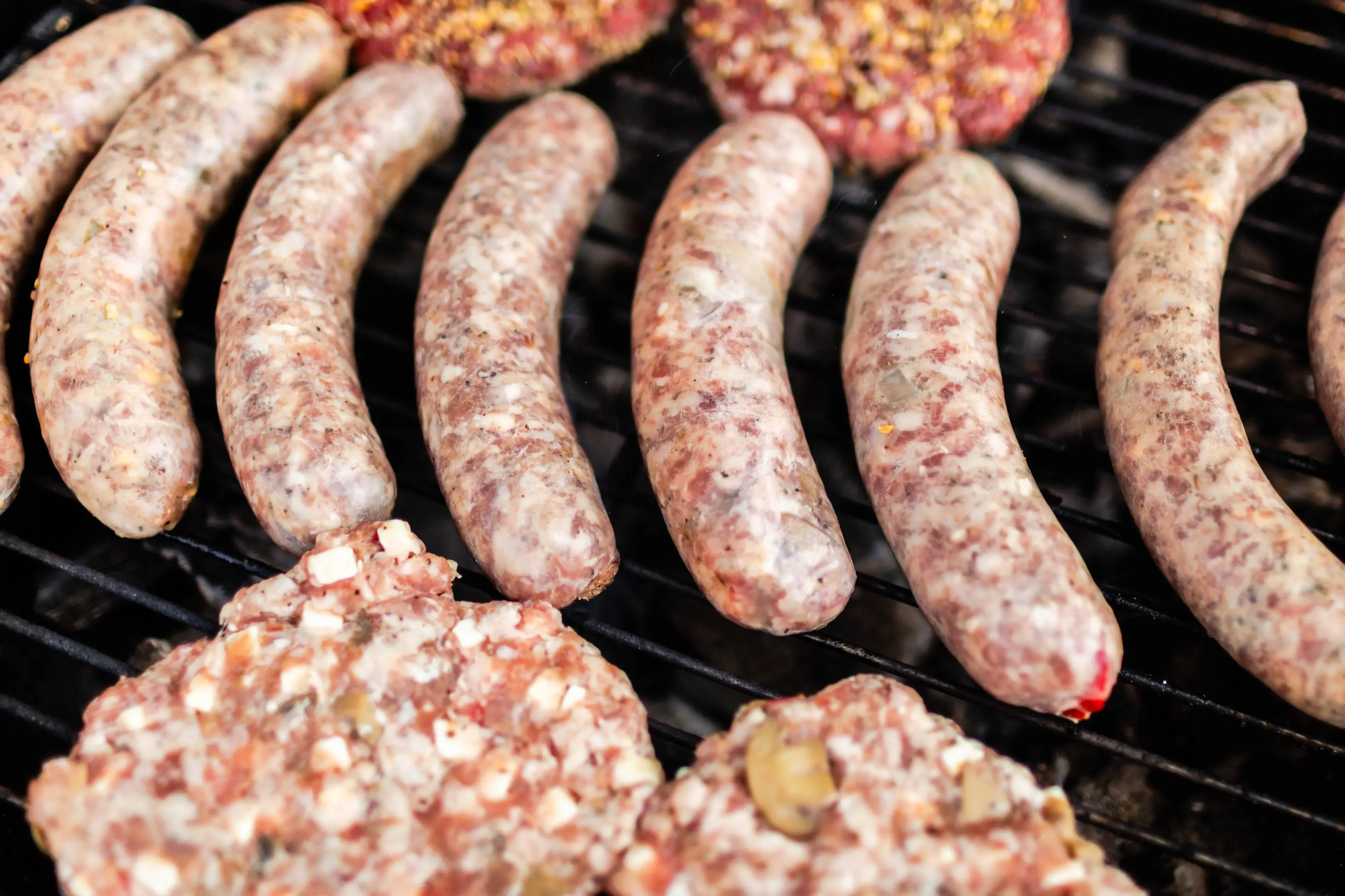 A grill with several different types of meat on it.