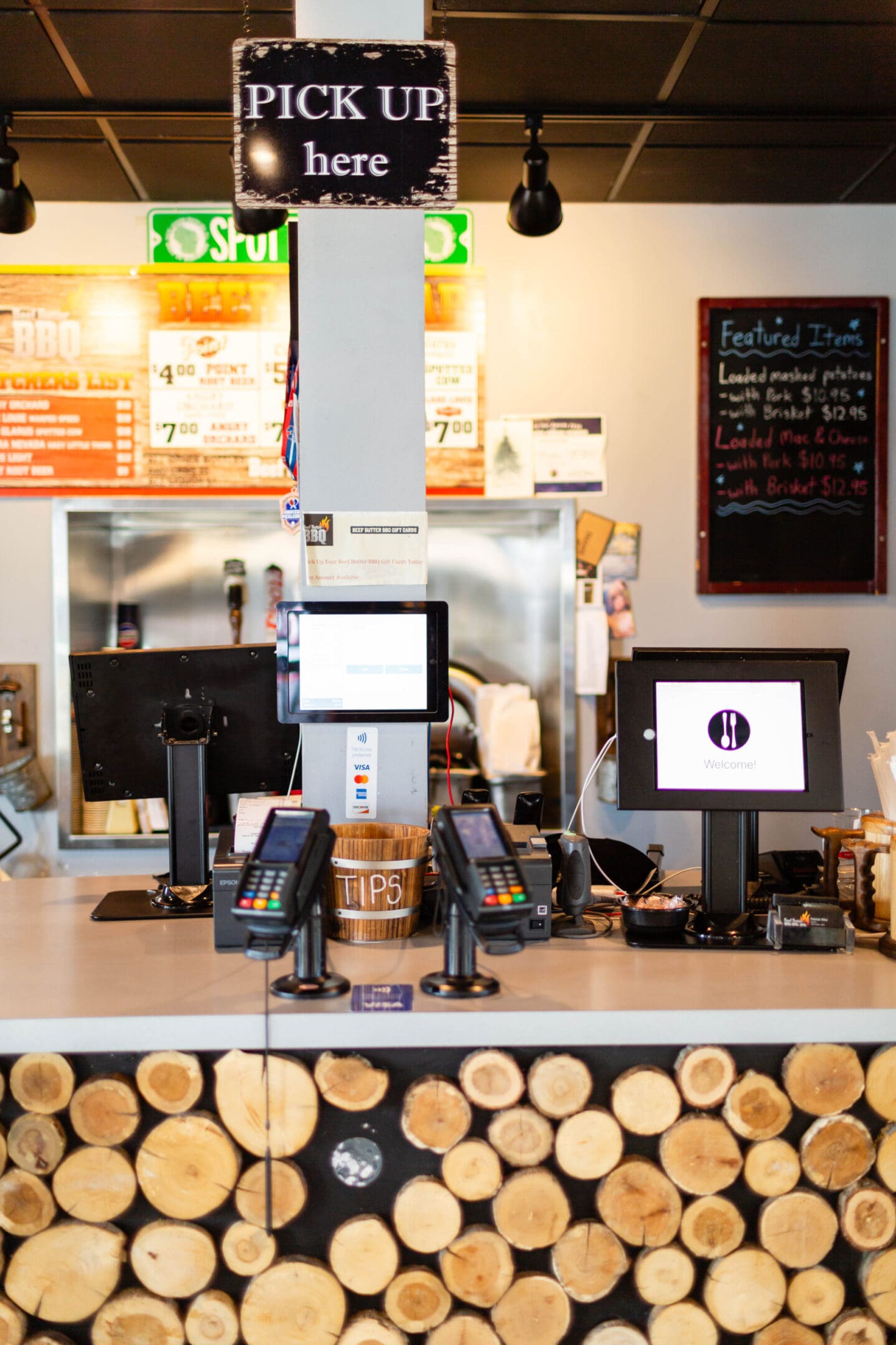 A counter with two computers and a menu board.