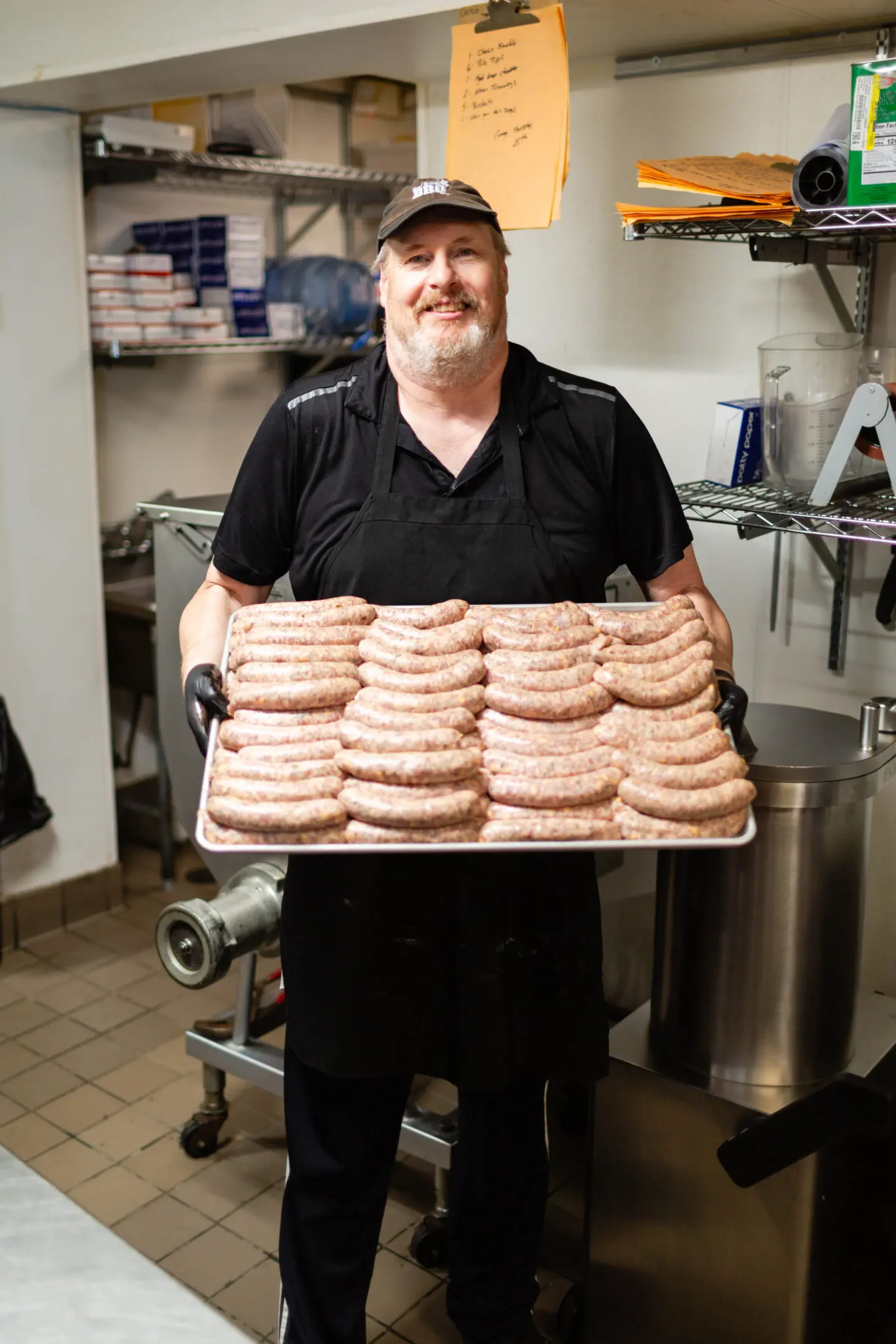 A man holding a tray of donuts in a kitchen.