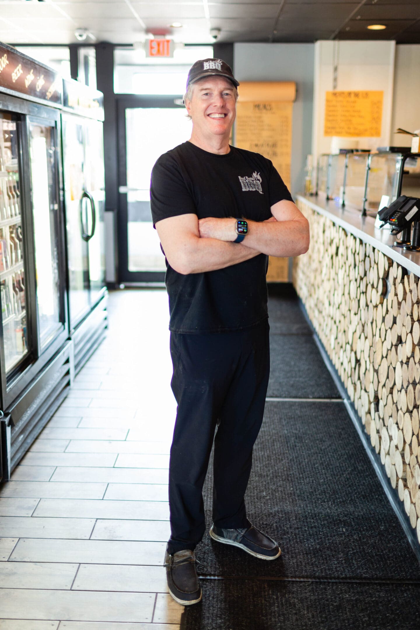 A man standing in front of a store with his arms crossed.