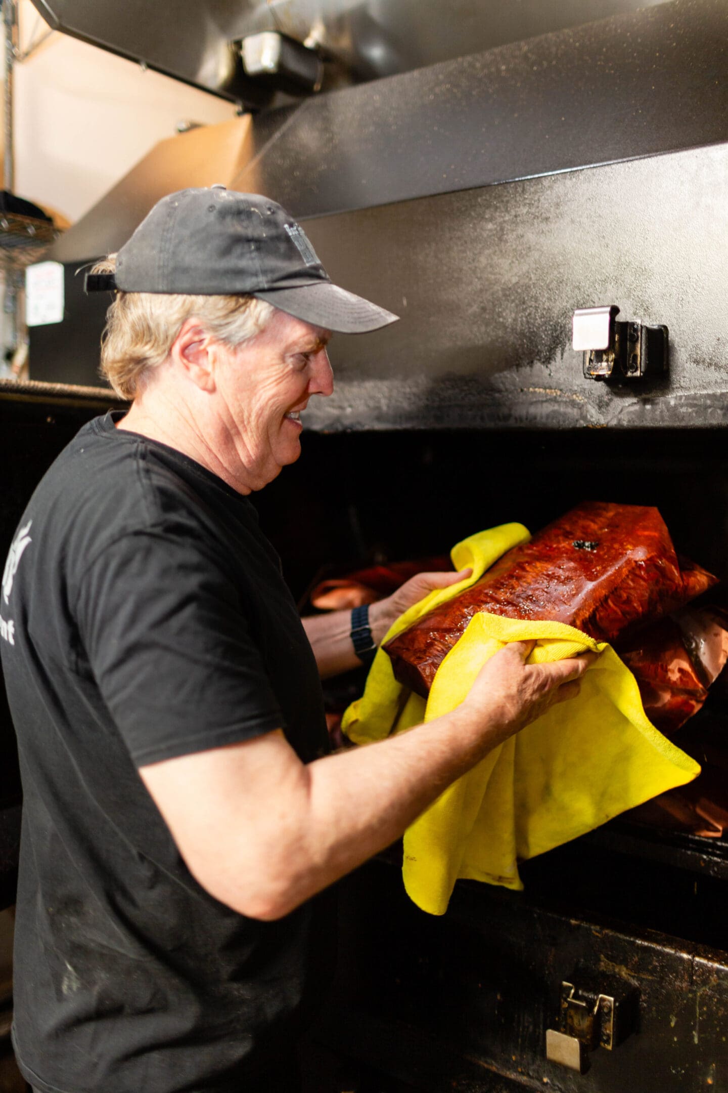 A man holding a yellow towel over a bbq.