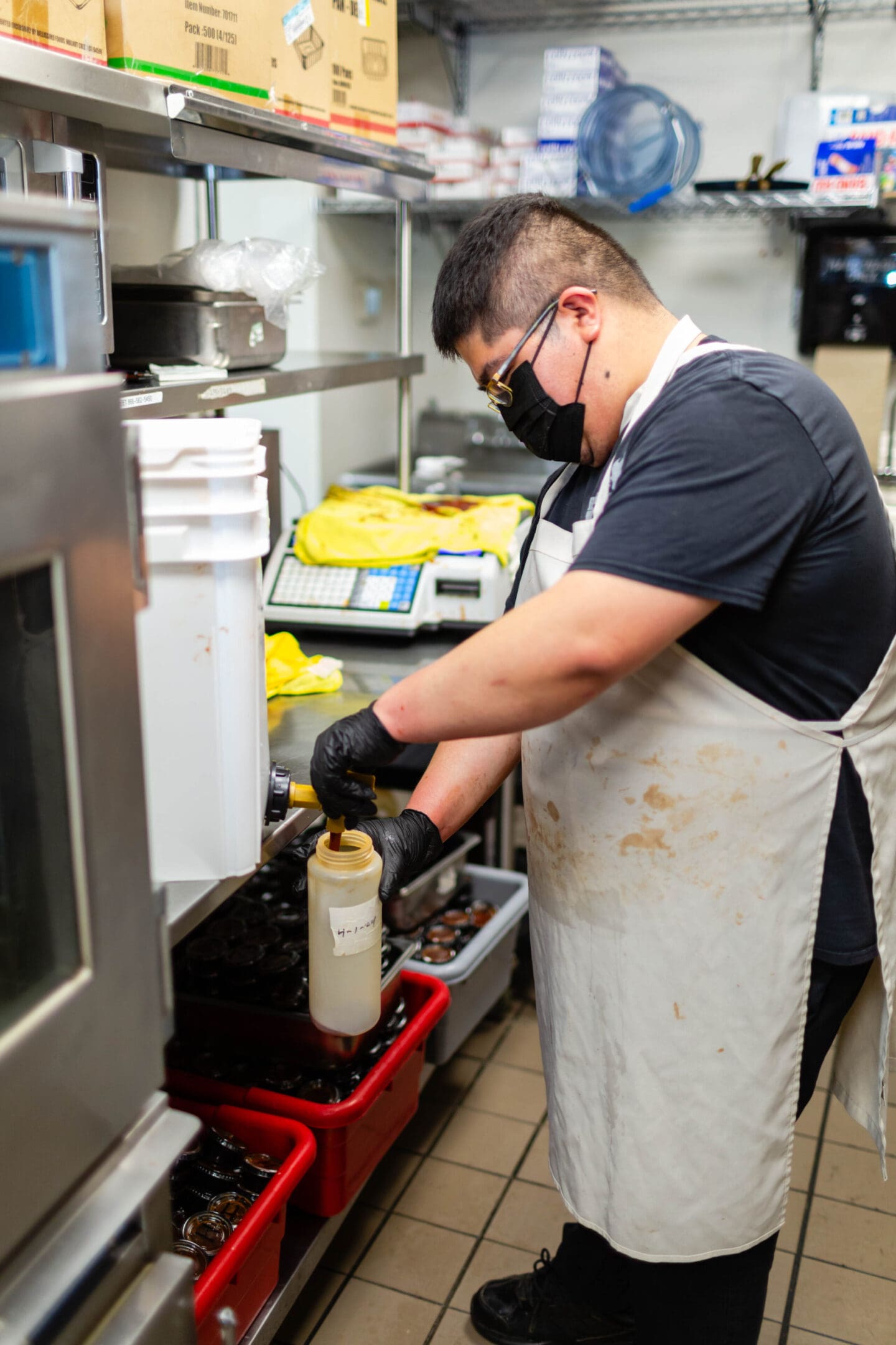 A man wearing gloves and a mask is working in the kitchen.