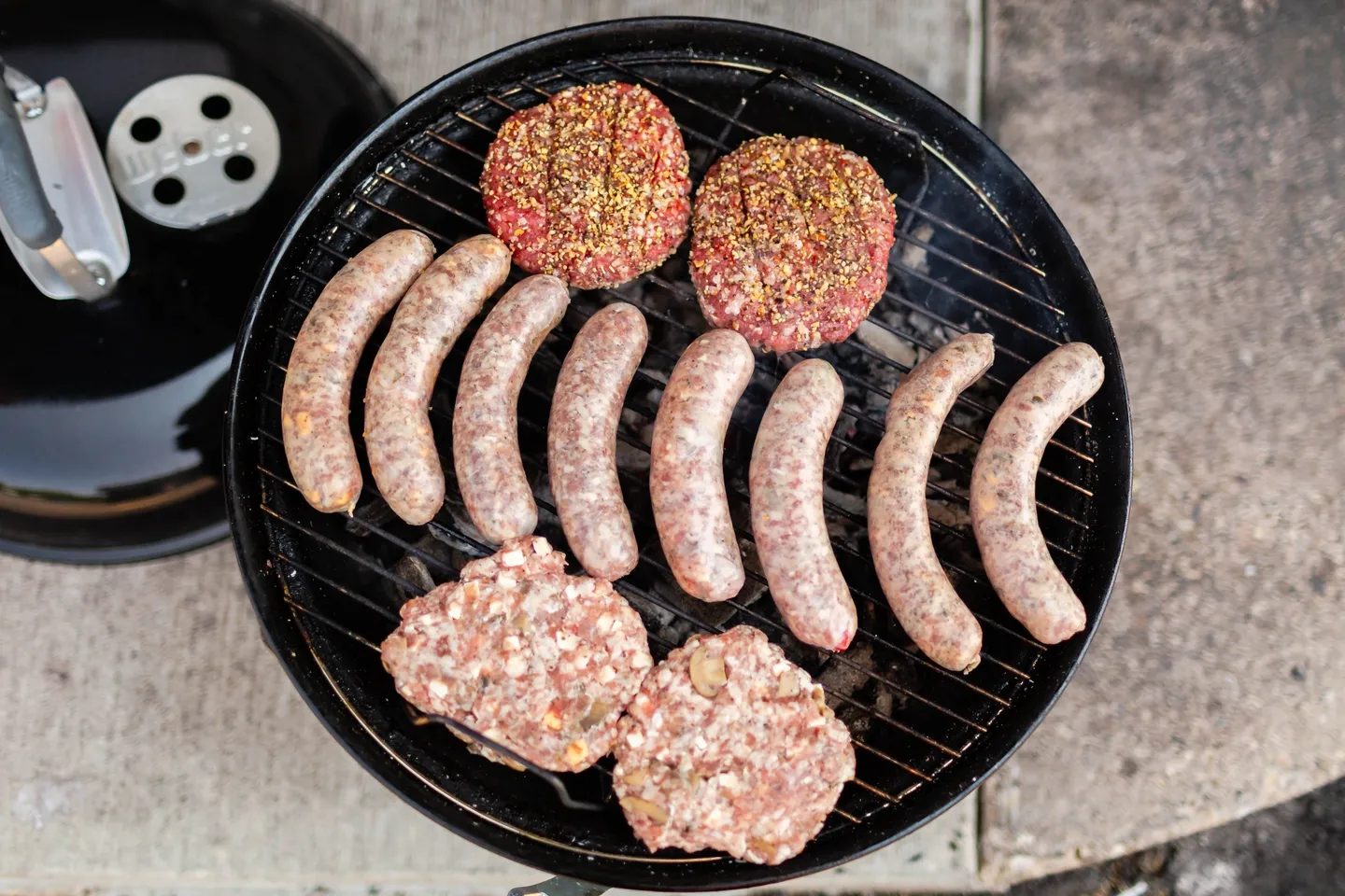 A grill with hamburgers and sausage on it.