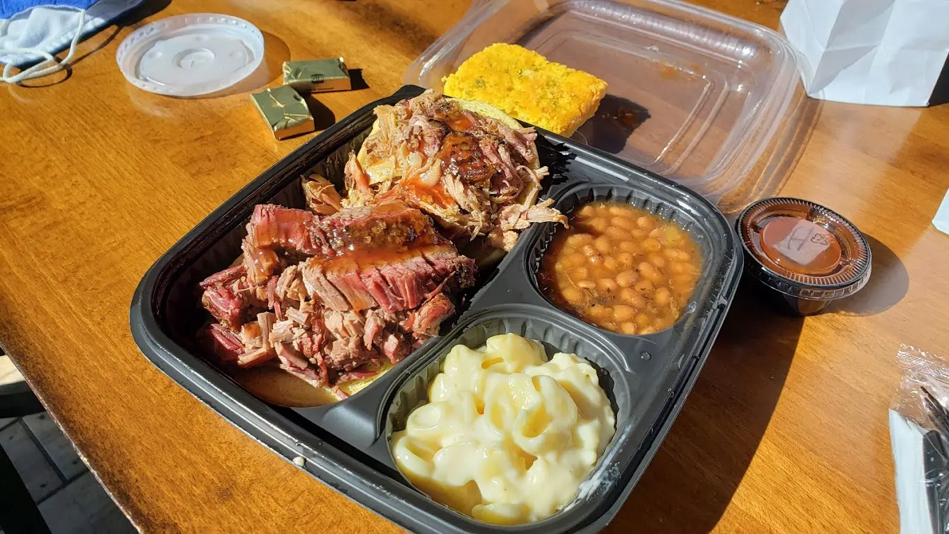 A tray of food with meat, beans and corn.