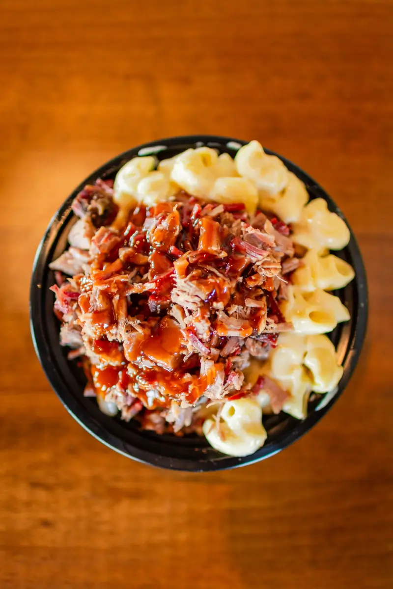 A bowl of pasta and meat on top of the table.