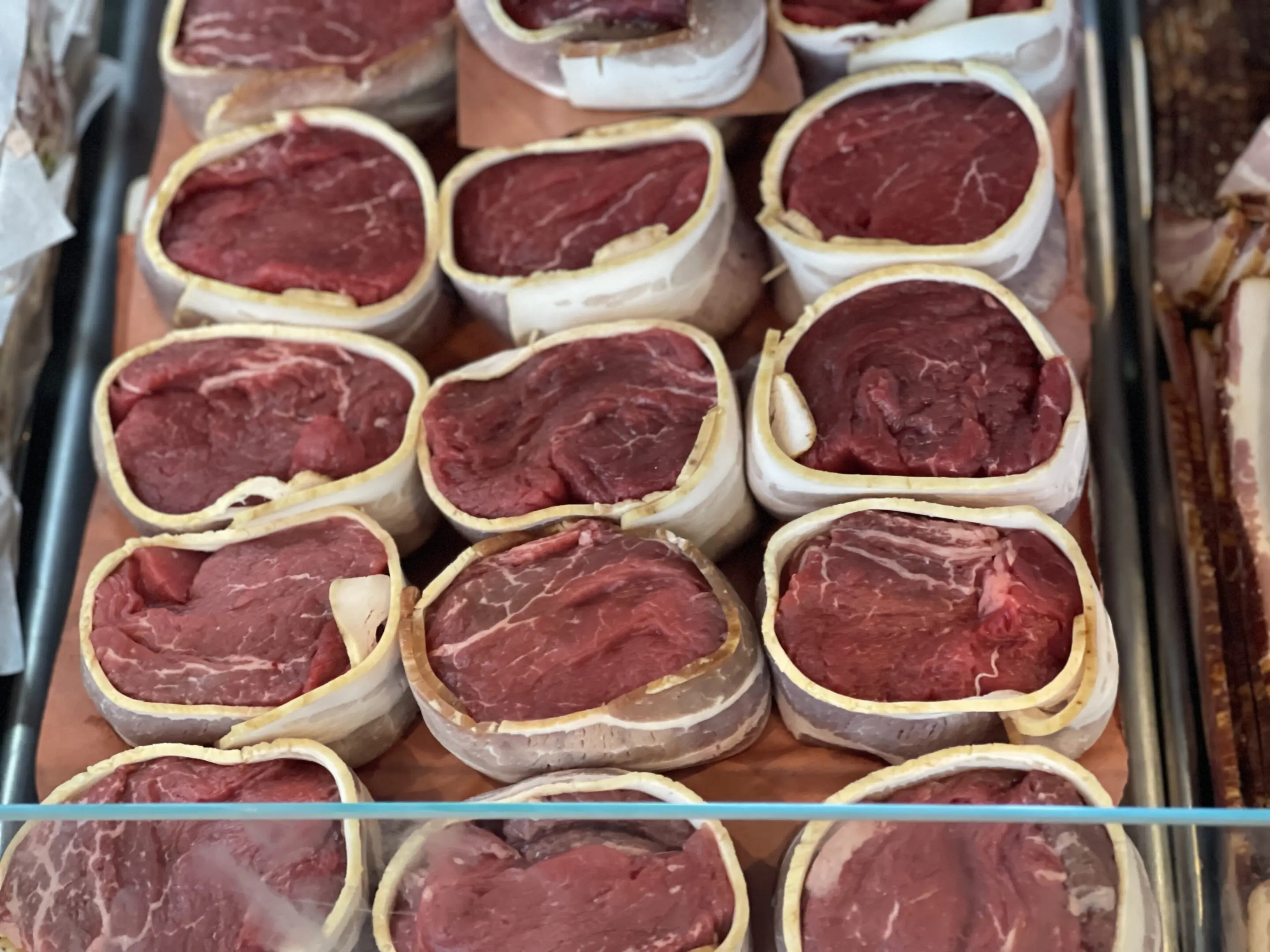 A bunch of raw meat in containers on display.